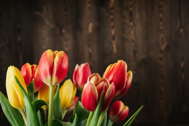 Strauß roter, gelber und rosa Tulpen auf einem braunen hölzernen Hintergrund kopieren Raum. Tulpen auf einem alten Holztisch lagen flach.