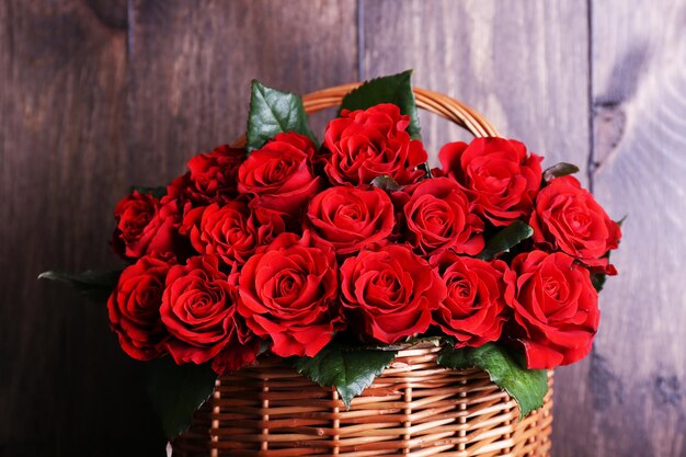 Strauß roter Rosen im Korb auf Holzhintergrund