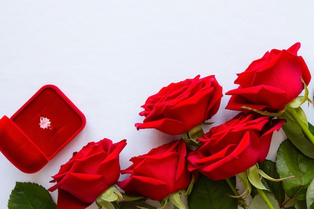 Strauß roter Rosen und eines Eherings auf Weiß