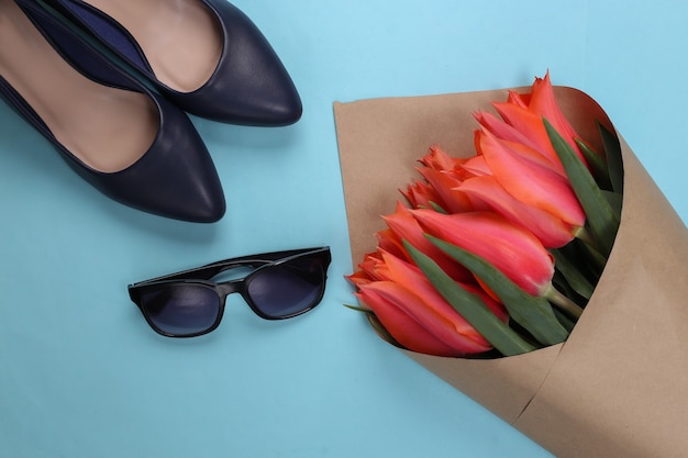 Strauß Tulpen, hochhackige Schuhe mit Sonnenbrille auf Blau