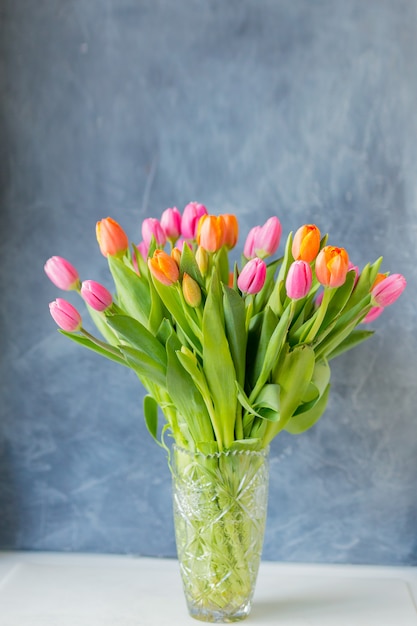 Strauß Tulpen in Vase. Frühlingsblumen . Blumenstrauß in Vase. Rosa und orange blühende Flora. Gemütliches Stillleben. Speicherplatz kopieren. Urlaubsgruß.