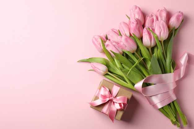 Strauß Tulpen und Geschenkbox auf rosa Hintergrund, Platz für Text