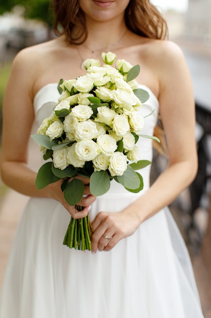 Strauß weißer Rosen in den Händen der Braut