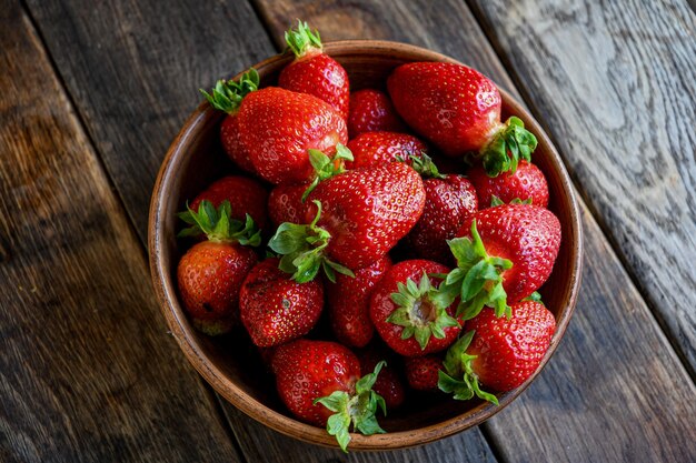 StrawberrHarvest hausgemachte Erdbeeren in Steingut auf einem alten Holztisch Kochen in der Küche