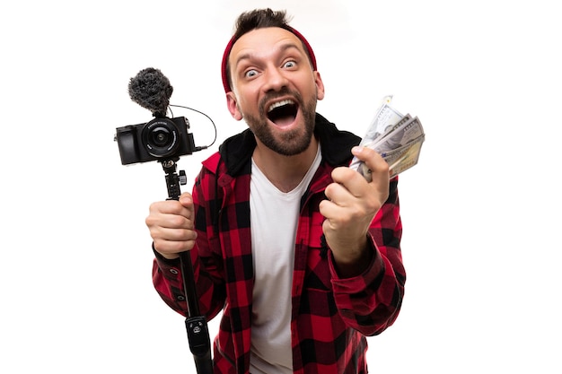 El streamer blogger feliz con una cámara y un fajo de dinero en sus manos se ríe emocionalmente mirando