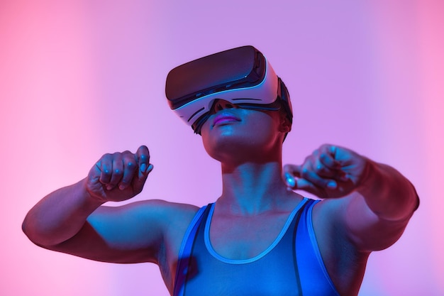 Streamer de mujer afroamericana jugando videojuegos usando gafas de realidad virtual en la sala de juegos