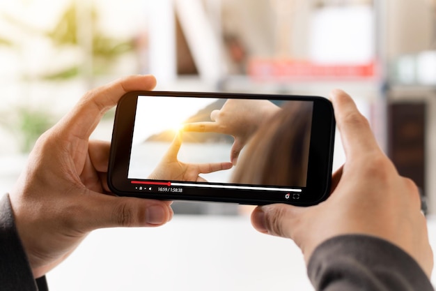 Streaming de películas en línea con teléfono inteligente Joven viendo una película en un teléfono móvil con un servicio de reproductor de video imaginario