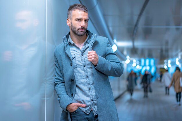 Street Style, cosmopolita retrato de una joven morena caucásica en un túnel del metro vistiendo una chaqueta gris americana