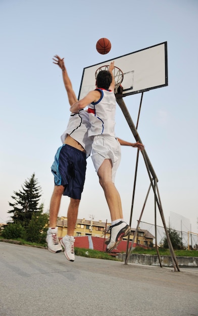 Streetball-Basketballspiel mit zwei jungen Spielern am frühen Morgen auf dem Stadtplatz