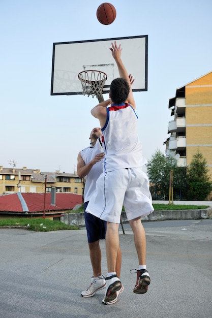 Streetball-Basketballspiel mit zwei jungen Spielern am frühen Morgen auf dem Stadtplatz