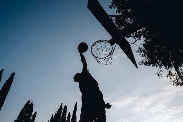 Streetball jogador de basquete executa um slam dunk