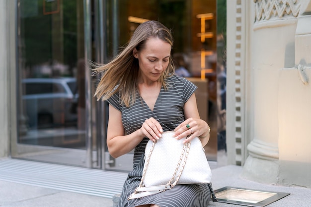 Streetstyle süße Bloggerin in grauem Kleid und analogen Handgelenken Stilvolle Frau