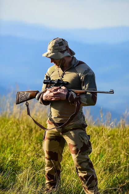 Streitkräfte Mann militärische Kleidung mit Waffe Brutaler Krieger Gewehr für die Jagd Bereit zu schießen Jäger halten Gewehr Jäger Berge Landschaft Hintergrund Fokus und Konzentration erfahrener Jäger