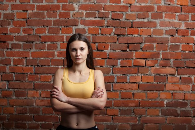 Strenge athletische Frau auf Backsteinmauerhintergrund