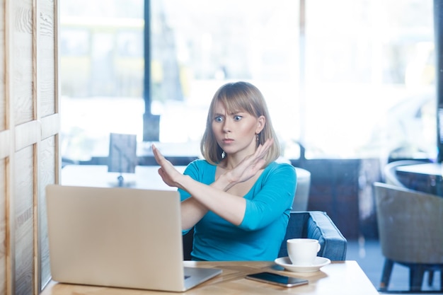 Foto strenge ernsthafte junge frau, die an einem laptop arbeitet, hat einen videoanruf, der die x-zeichen-geste zeigt