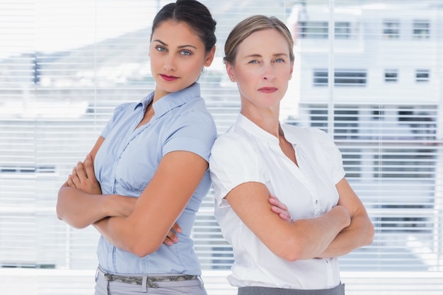 Strenge Geschäftsfrauen, die zurück zu Rückseite stehen