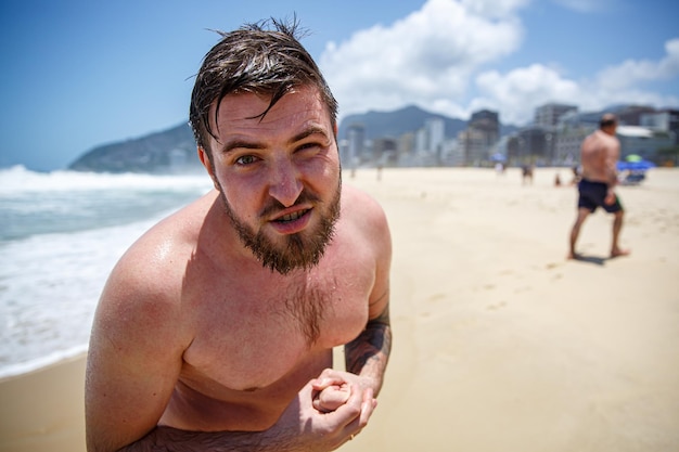 Strenger bärtiger Mann ohne Hemd am Strand