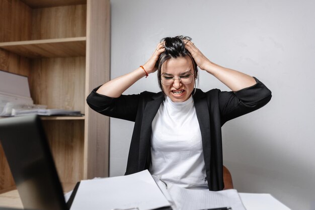 Foto stress bei der arbeit die arbeiterin im büro hält ihren kopf in wut und frustrationsstress