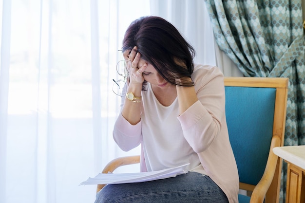 Stress-Kopfschmerzen, Migräne, verärgerte Frau mittleren Alters, die ihren Kopf mit den Händen hielt