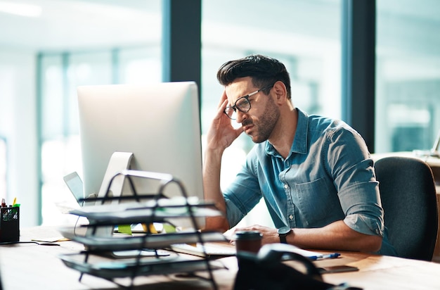 Stressangst und Sorgen mit einem Geschäftsmann, der sich frustriert, irritiert und verärgert über Arbeit und Fristen fühlt Unglücklicher und negativer männlicher Angestellter, der in seinem Büro an Kopfschmerzen oder Migräne leidet