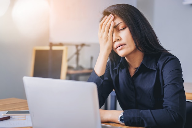 Stressige Geschäftsfrau, die im Büro müde und gelangweilt arbeitet.