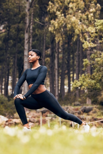 Stretching-Fitness und schwarze Frau machen Ausfallschritte in der Natur für körperliches Training und Sport im Wald beim Bergwandern und weibliche Person streckt Beine für Aufwärmtraining und Wellness für Leistung