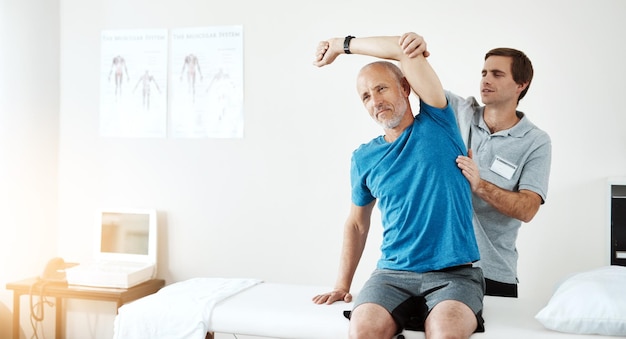 Stretching-Physiotherapie und ein Mann mit einem Arzt für Rehabilitation, Fitness und Gesundheitsunterstützung. Gesundheitssporttraining und ein Physiotherapeut mit einem älteren Patienten und Armdehnung nach einer Verletzung