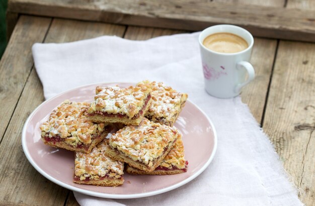 Streuselkuchen gefüllt mit Rosenmarmelade, serviert mit Kaffee. Rustikaler Stil.