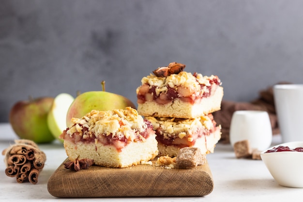 Streuselkuchen mit Apfel-, Beerenmarmeladen- und Gewürzfüllung und einer Tasse Kaffee.