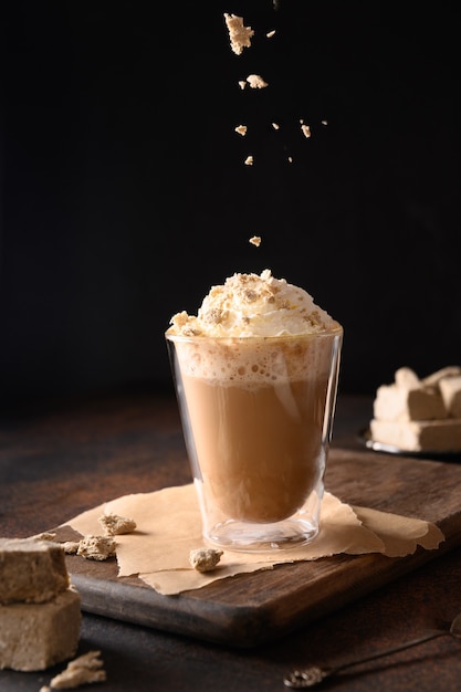 Streut Halawa in trendigem Rezept Kaffee Latte mit Halva in moderner Glastasse auf dunklem Hintergrund