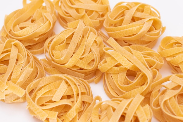 Streute klassische italienische rohe Eier Fettuccine auf weißem Tisch