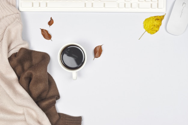 Strickjackemantel mit Tasse Kaffee und Laptop, Herbstlaub auf Weiß.