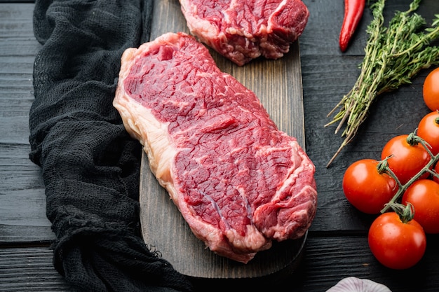 Striploin-Steak, Metzgerei mit rohem Rindfleisch, auf schwarzem Holztisch