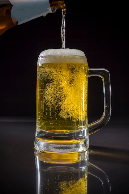 Strömendes Bier, Pint Glas mit Bier auf schwarzem Hintergrund, Glas kaltes helles Bier mit Schaum