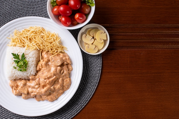 Stroganoff de pollo acompañado de arroz, ensalada y paja de papa