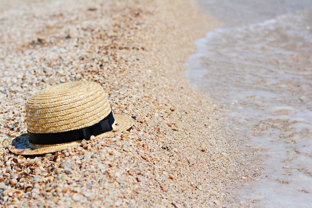 Strohhut auf Sand und Wasser