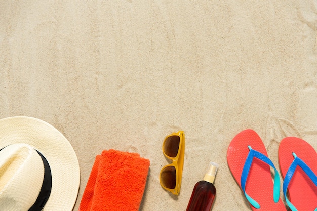 Strohhut, Flip-Flops und Sonnenbrille auf Strandsand