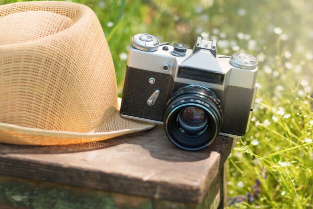 Strohhut und die Vintage-Kamera auf einem Holzstuhl im Sommergarten