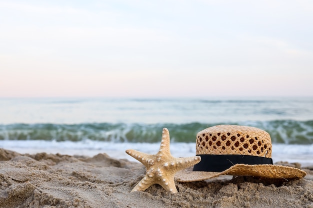 Strohhut und Seestern auf schönem Sand am Meer