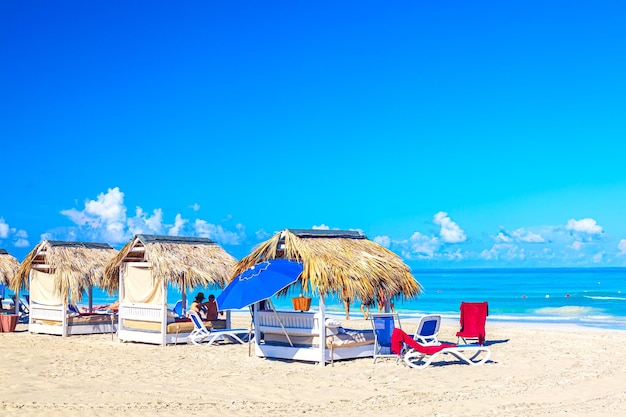 Strohschirmbetten am Sandstrand am Meer und am Himmel. Urlaub-Hintergrund. Idyllische Strandlandschaft. Varadero, Kuba