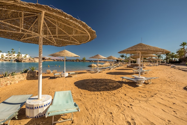 Strohschirme und Liegen am wunderschönen tropischen Strand