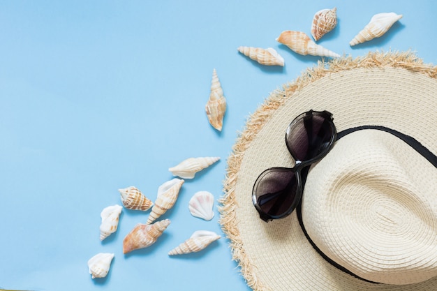 Strohstrand Sunhat und Sonnenbrillen auf schlagendem Blau.