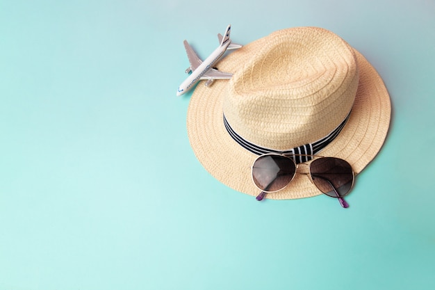 Strohstrandhut, Sonnenbrille und weißes Flugzeug im Sommer