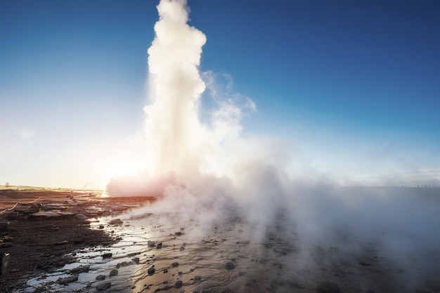 Strokkur-Geysir-Eruption in Island. Fantastische Farben leuchten durch den Dampf. Schöne rosa Wolken in einem blauen Himmel