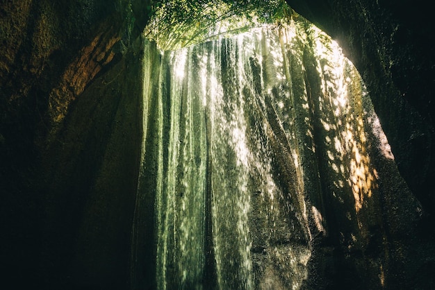 Strom des Wasserfalls Tucad Cepung, der in die Höhle Bali Indonesien hinunterfließt