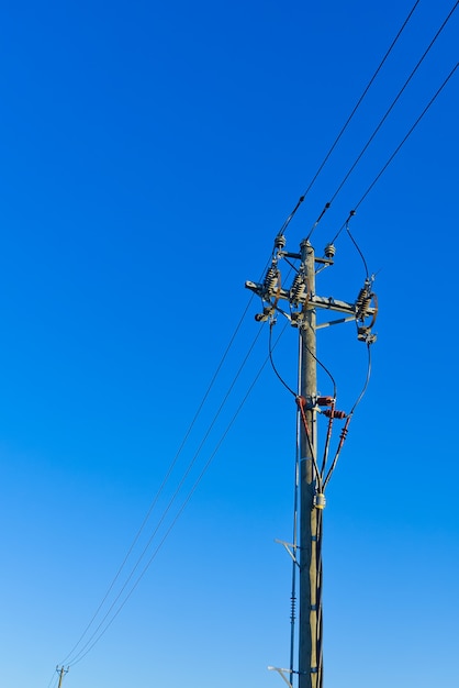 Stromlinien Sky Lines und Verbindungen auf einem Holzpfosten. hölzerner Strompfosten gegen blauen Himmel