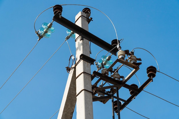 Strommast Elektrischer Pfosten mit Stromkabeln Stromleitungen und Drähte gegen strahlend blauen Himmel