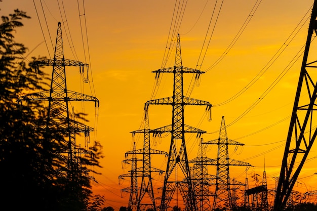 Strommasten tragen die Stromversorgung über eine ländliche Landschaft Selektiver Fokus Schöner Sonnenuntergang gegen Metallmasten