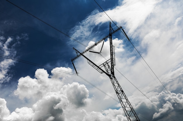 Stromübertragungsmast vor blauem Himmel silhouettiert