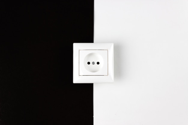 Stromverbrauch Tag und Nacht. Weiße Steckdose auf schwarzem und weißem Papierhintergrund.